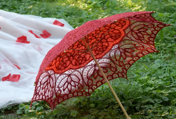 Yeşil Çimenlerin Üzerinde Kırmızı Bir Dantel Şemsiye Yatıyor — Stok fotoğraf