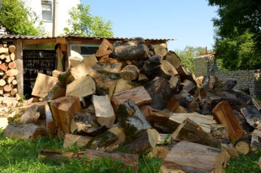 Odun yığınının yanında bir yığın kuru odun var. Kış için yakacak odun hazırlıyorum. Kesilmiş odunların arka planı. Kışın ısınmak için odun hazırlarlar..