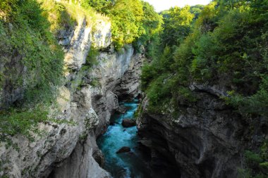 Çukurda, dipten akan mavi bir nehir var. Dağ geçidi, dağ nehrinin sularında taş kıyıları asılı..