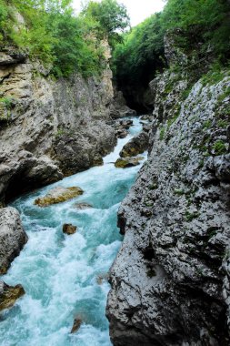 Çukurda, dipten akan mavi bir nehir var. Dağ geçidi, dağ nehrinin sularında taş kıyıları asılı..