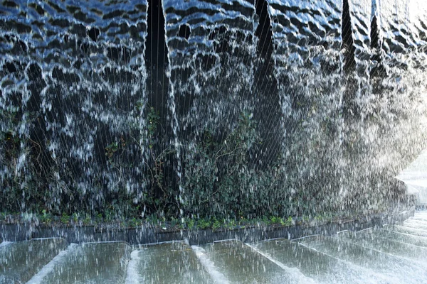 Pared de agua con cascadas. Agua que fluye sobre una textura de fondo de piedra. Cascada artificial en el parque. —  Fotos de Stock