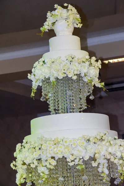 Large three-tiered cake on separate trays. The wedding cake is highlighted in purple. A beautifully decorated cake for a holiday, brought in in the evening