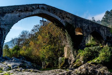 A Roman bridge built in the late 13th century that goes over the Sella River in Cangas de Onis Spain. clipart
