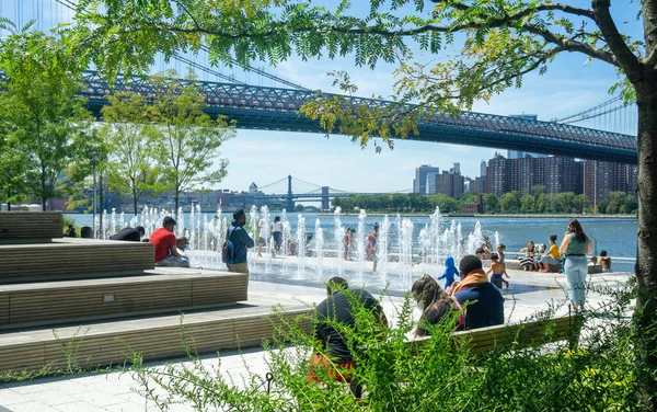 Brooklyn, New York / ABD - 8 / 20 / 20: Domino Park 'ın çeşme manzarası ve oturma merdivenleri. Doğu Nehri ve Williamsburg Köprüsü.