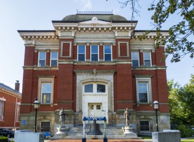 Northampton, MA - ABD - 24 Ağustos 2025 Tarihi kırmızı tuğlalı Northampton Memorial Hall girişi heykelleri ve USS Northampton gemi çanlarıyla.