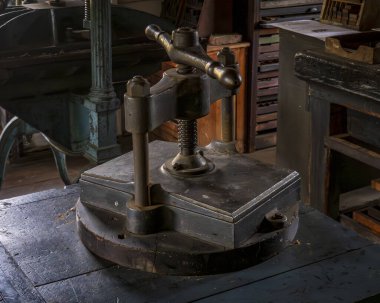 Monroe, NY - ABD - 6 Eylül 2025 Müze Köyü 'ndeki basımevinde antika bir demir kitap presi ve ilgili ekipmanların yakın çekimi, geleneksel ciltleme yöntemlerini sergiliyor.