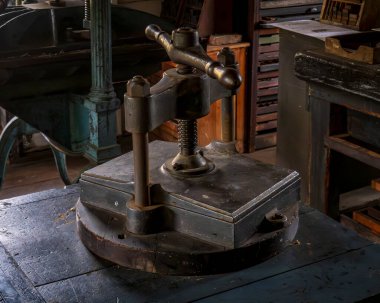 Monroe, NY - ABD - 6 Eylül 2025 Müze Köyü 'ndeki basımevinde antika bir demir kitap presi ve ilgili ekipmanların yakın çekimi, geleneksel ciltleme yöntemlerini sergiliyor.