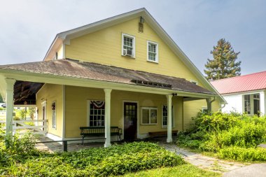 Monroe, New York - 6 Sep 2025 Monroe, New York 'taki Müze Köyü' ndeki sarı boyalı sergi salonunda vatansever dekorasyonlarla süslenmiş ve yemyeşil peyzajlarla çevrili bir hoş geldin verandası bulunuyor..