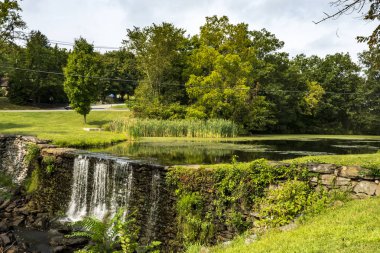 Monroe, NY - ABD - 6 Sep 2025: Monroe, New York 'ta bulunan Picturesque Smith' s Mill barajı ve göleti, sakin bir şelale, sakin bir su ve dingin bir gökyüzü altında canlı yeşil bir manzara