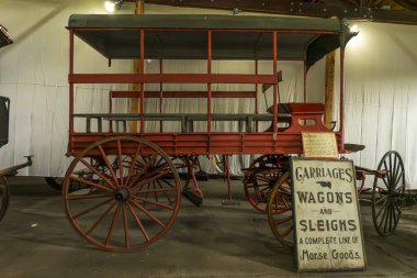 Monroe, NY - ABD - 6. Sep 2025 Tarihi kırmızı ahşap araba Müze Köyü 'nde vintage taşıma levhasının yanında tepe örtüsü sergilenmektedir..