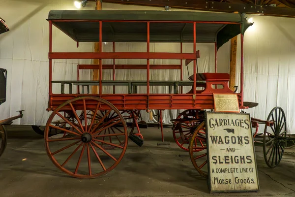 Monroe, NY - ABD - 6. Sep 2025 Tarihi kırmızı ahşap araba Müze Köyü 'nde vintage taşıma levhasının yanında tepe örtüsü sergilenmektedir..