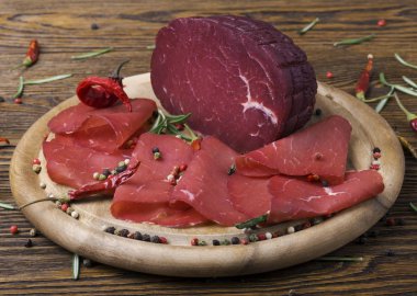 Bresaola biberiye ve kırmızı biber bir delikanlı ile ahşap bir tahta üzerine dilimlenmiş