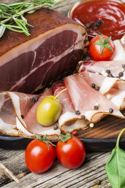 Delicious smoked ham on wooden table with rosemary, pepper and cherry tomatoes. Top view