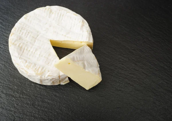 大まかなグラファイトの背景上のカット スライスをカマンベール ラウンド フランスのチーズ — ストック写真