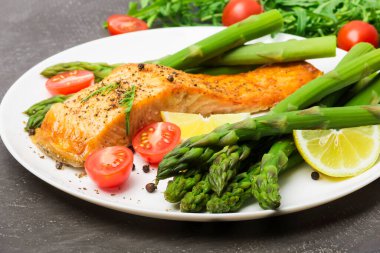 Fırında somon kuşkonmaz ve domates ile otlar ile süslenmiş