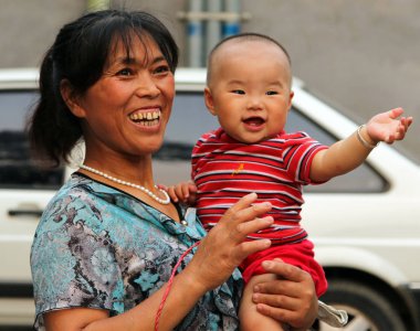 Beijing, Çin - 4 Temmuz 2011: Mutlu Çinli kadını kucağında bir bebekle. Şimdi her ailede birden fazla çocuk var Çin Doğum kontrol, iptal edildi
