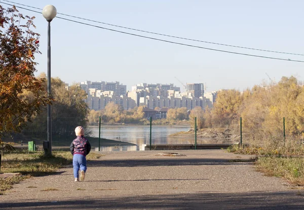 Sırt çantalı küçük kız nehir kenarında yürüyor. 