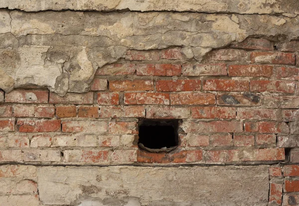 Dışarıda yıllanmış kırmızı tuğla duvar var.