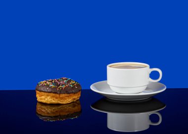 Lezzetli donut ve beyaz kahve ile mavi arka planda yansımalı kahve.