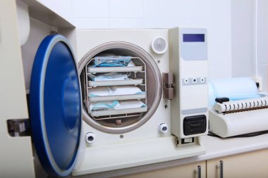 Klinikteki diş aletlerinin sterilize edilmesi için bir dolap. İçerideki fotoğraflarda insanlar yok. Boşluğu kopyala.