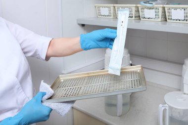 Mühürlü el sanatları paketlerinde steril diş aletleri. Kliniklerde kısırlık ve hijyen kavramı. Yüzü olmayan tanınmamış bir fotoğraf. Boşluğu kopyala.