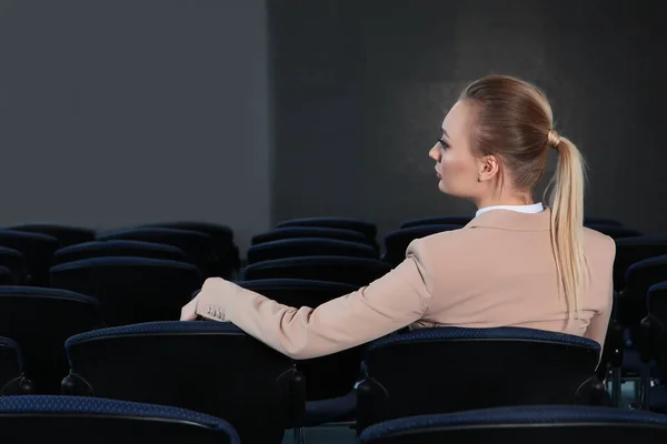 Eine Geschäftsfrau im leichten Business-Anzug sitzt in einem leeren Besprechungsraum. Das Konzept der Finanzkrise. Kopie des Raumes. Unerkennbares Foto. — Stockfoto