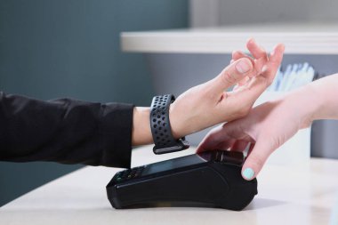 Alımlar ve hizmetler için online ödeme. Elinde saat ve ödeme terminali olan bir el. Tanımlanamayan bir fotoğraf. Boşluğun kopyası.