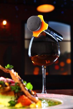 Mikrofon bir bardak şarabın üzerinde duruyor. Karaoke restoranı konsepti. Odada karanlık bir arka plan fotoğrafı. Boşluğu kopyala.