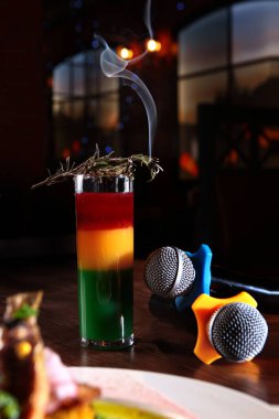 Masada iki karaoke mikrofonu üç renkli alkollü kokteylin yanında. Karaoke restoranı ya da kafe kavramı. Uzayı kopyala İçerideki fotoğraf..