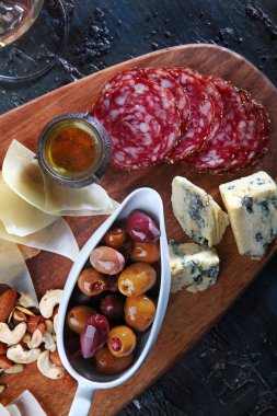 Tahtada peynirli ve sosisli zeytin. Beyaz şaraplı bir aperatif. Uzayı kopyala Üst görünüm.