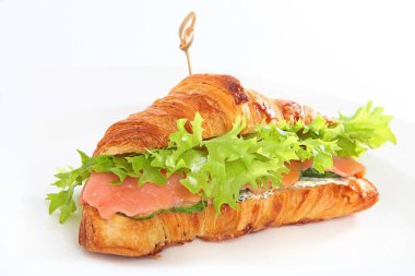 Kırmızı balıklı kruvasan, beyaz arka planda yumuşak peynir ve salatalık. Makro fotoğraf. İzole bir nesne. Boşluğu kopyala.