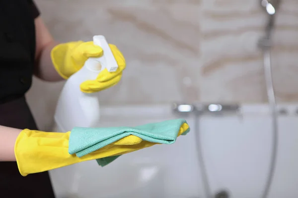Cleaning service in an expensive hotel or at home. A woman in a uniform and rubber gloves.Cleanliness and hygiene in the bathroom.Unrecognizable photo. Only hand. Copy space.