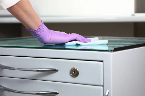 Disinfection of furniture in the dental office. Preparing the office for receiving patients. Close-up of a gloved hand. Copy space. Unrecognizable photo.