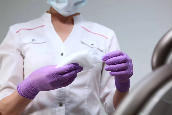 Uma enfermeira segura um pano para limpar superfícies no consultório do dentista. Desinfecção na clínica. Uma foto irreconhecível. Cópia do espaço . — Fotografia de Stock