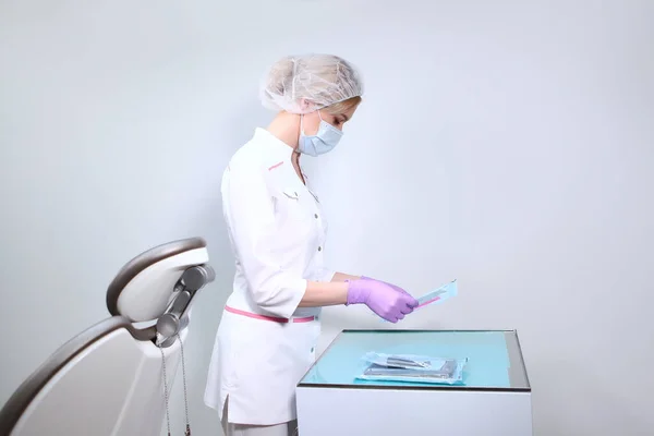 Uma Enfermeira Uniforme Máscara Médica Segura Instrumentos Dentários Estéreis Embalados — Fotografia de Stock