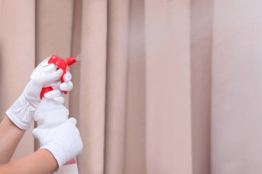 Hizmetçi plastik şişeden oda spreyi sıkar. Beyaz pamuk eldivenli eller. Tanımlanamayan bir fotoğraf. Sadece el. Uzayı kopyala Otel işi kavramı..