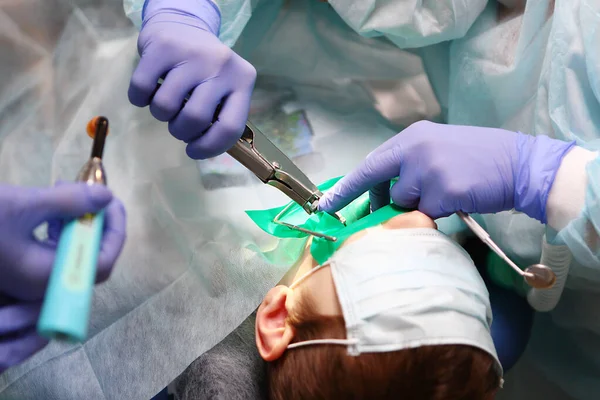 Diş ameliyatı. Bir pediatrik diş cerrahı, genç bir çocukta derin bakterileri tedavi etmek için ameliyat eder. Sağlık ve önleme kavramı. Boşluğu kopyala.