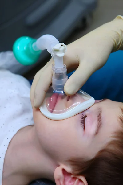 A little boy under anesthesia. Breathing mask on the face. Concept of health care and life saving. Copy space.Vertical photo.