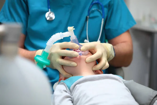 Küçük bir çocuğu diş ameliyatına hazırlıyorum. Genel anestezi. Çoklu bebek dişi tedavisinde kullanılıyor. Ciğerlerde yapay havalandırma cihazı. Boşluğu kopyala.