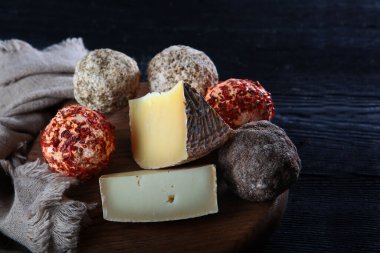 Peynir ve peynir çeşitleri ve acı biberli. Peynirler yuvarlaktır. Hareketsiz yaşam kavramı. Boşluğu kopyala. Fotoğraf siyah arkaplanda..