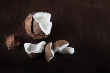 Hindistan cevizi parçalara ayrılmış. Karanlık bir arka planda fotoğraf. Boşluğu kopyala. Üst görünüm.