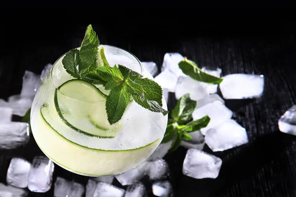 Pepino fresco e limonada de casa da moeda em um jarro de vidro. Refrigerante. Cubos de gelo na bebida. Cópia do espaço. Foto vertical em um fundo preto.Vista superior . — Fotografia de Stock