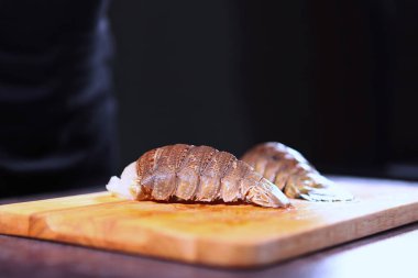 Tahtada ıstakoz kuyruğu. Taze deniz ürünleri. Deniz ürünleri pişirmek. Doğal protein. Siyah arkaplan..