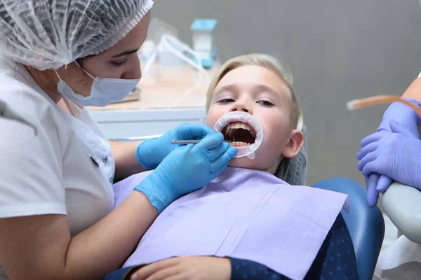 Higiena jamy ustnej u dzieci. Dentysta dziecięcy czyści dzieciom zęby. Zdjęcie we wnętrzu na jasnym tle. Pojęcie zdrowych zębów. — Zdjęcie stockowe