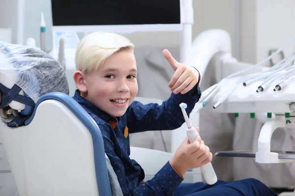小児科の受付で元気な男の子 子供は電動歯ブラシを持っています 医療と疾病予防の概念 スペースのコピー — ストック写真