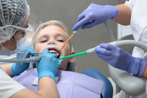 Dentist brushing the teeth of a little boy. Professional hygiene of the oral cavity. Comfort for patients. Concept of health care and disease prevention. Pediatric dentistry. Hands in protective — Stock Photo, Image