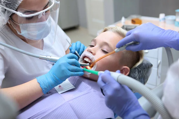 歯医者は小さな男の子の歯を磨く。口腔の専門衛生。医療と疾病予防の概念。小児科。保護手袋の手. — ストック写真