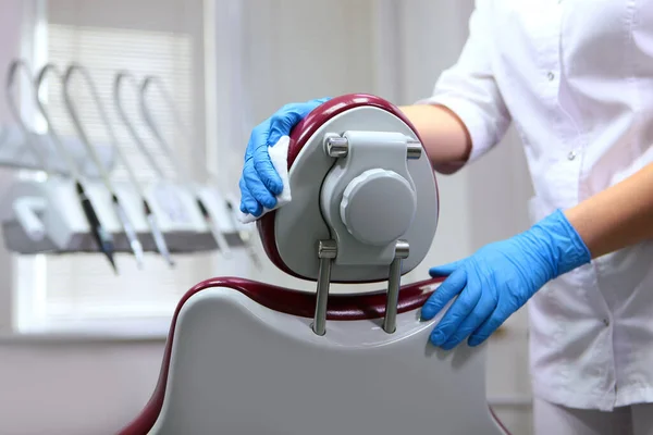 Disinfection in the dental office. Preparing the office for receiving patients. A doctor\'s assistant wipes the headrest of the dental chair. Copy space. Unrecognizable person.
