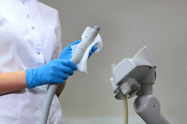 Asistanı ıslak bir bezle ekipmanı siler. Diş muayenehanesinde dezenfeksiyon. Hijyen ve hijyen kavramı. Tanımlanamayan kişi. Boşluğu kopyala.