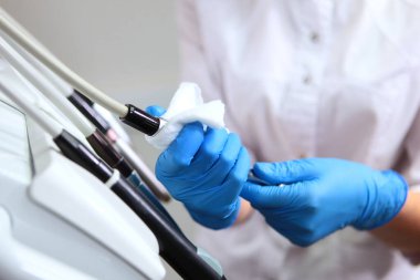 Diş teçhizatı dezenfeksiyonu. Diş asistanı hasta almadan önce aletleri dezenfekte eder. Klinikte hijyen ve hijyen kavramı. Uzayı kopyala. Kapat